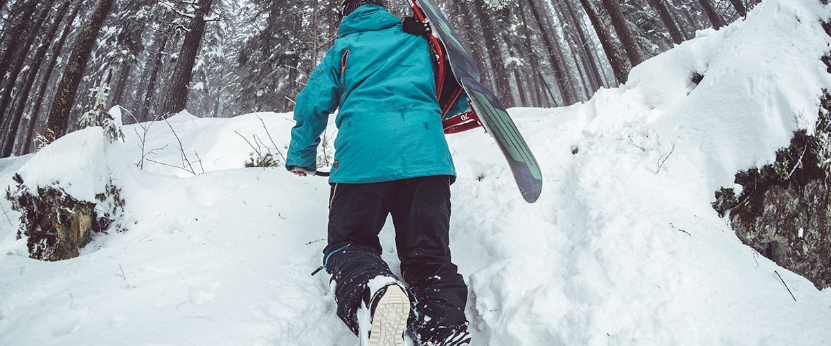 Snowboarder treks up the snow