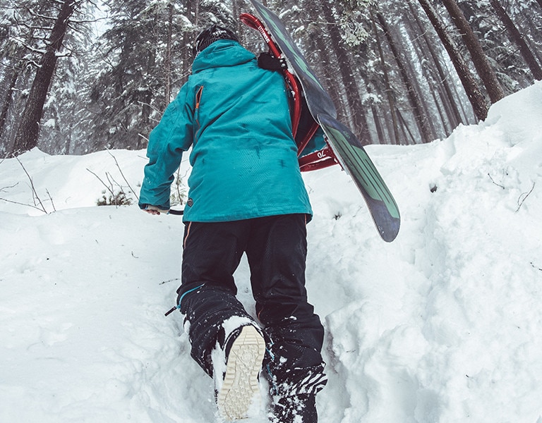 Snowboarder treks up the snow