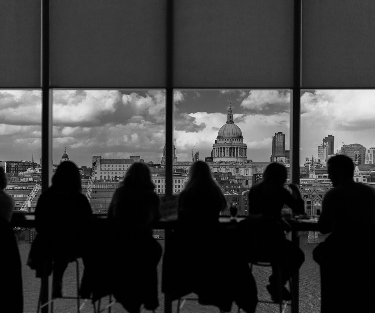 people sitting in an office building, silhouetted against backdrop of a city