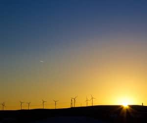 sun rising over open landscape with wind turbines