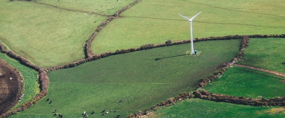 Wind turbine stands over green fields