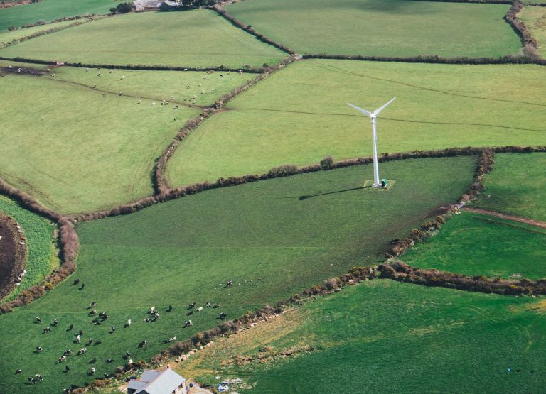 Wind turbine stands over green fields