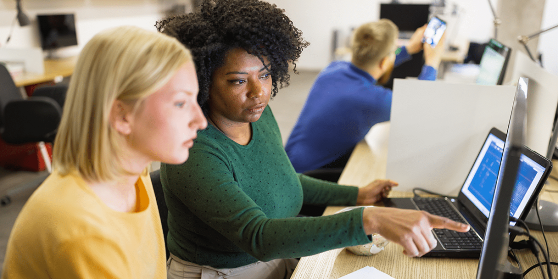 Two women talking while looking at a computer screen