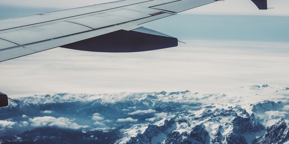 An airplane flying over mountain landscape representing responsibility for GHG