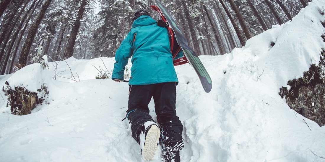 Snowboarder treks up the snow