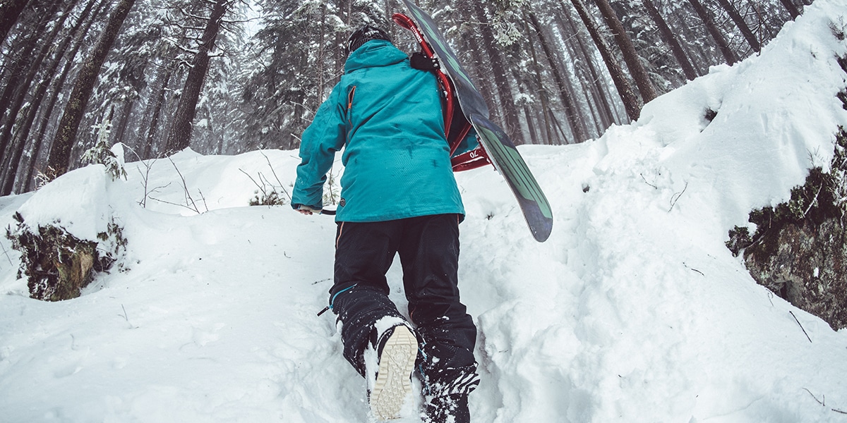 Snowboarder treks up the snow