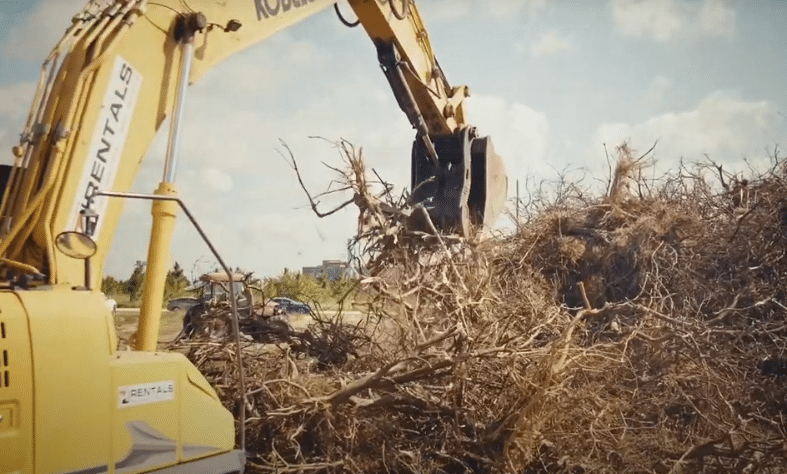 An excavator moving feedstock for the Central Florida Citrus Project.
